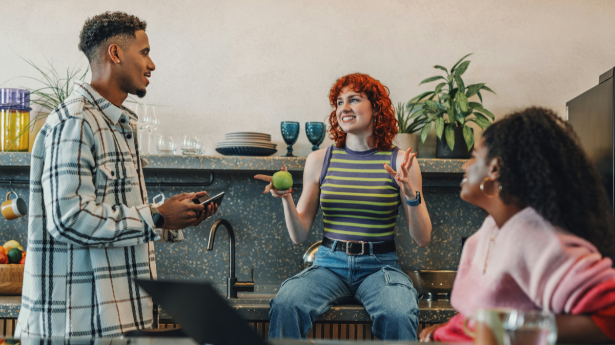 2 women and a man sitting in an office pantry discussing something